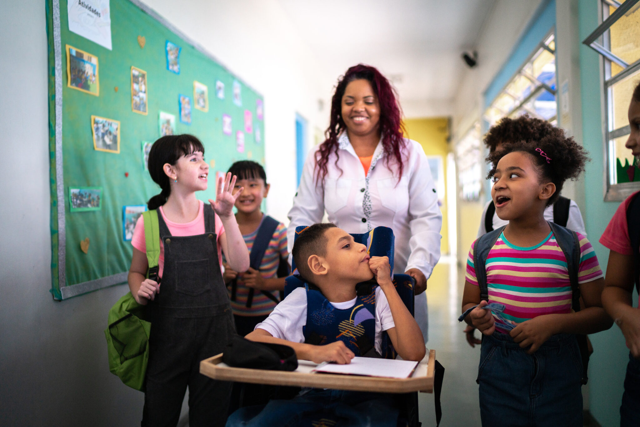 Teacher and students walking in the corridor at school - including a person with special needs